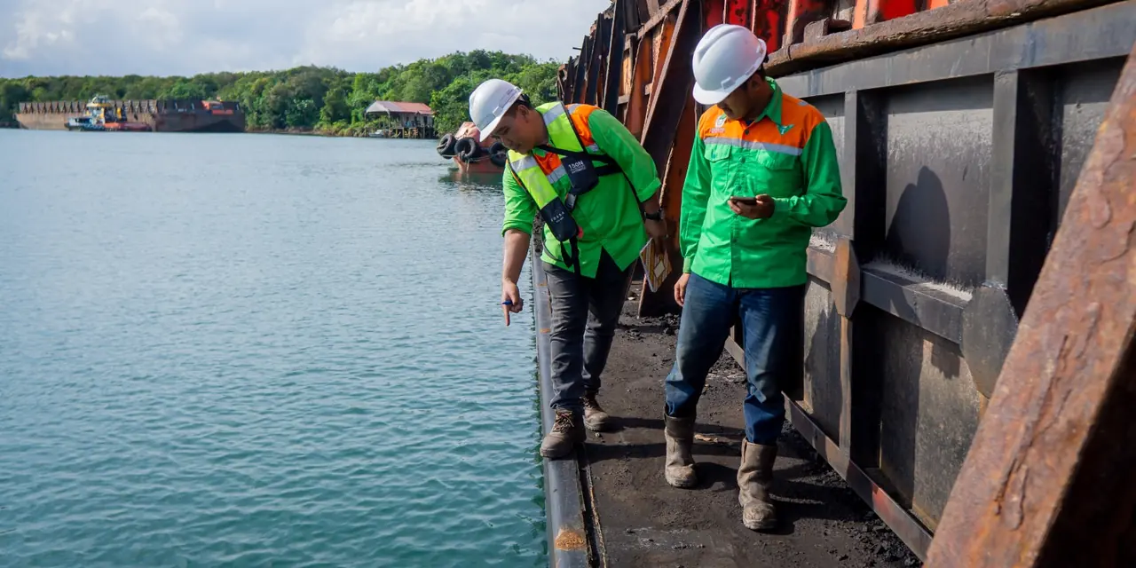Surveyors inspecting the side of a barge on the waterway