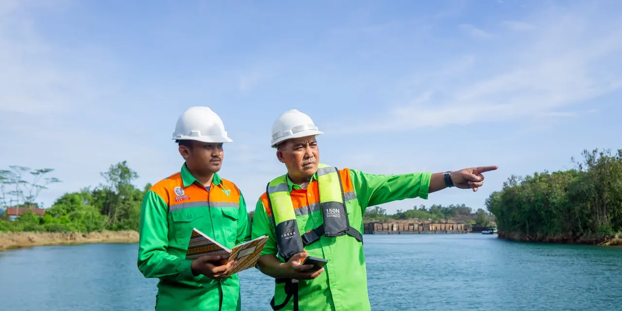 Surveyors reviewing field notes and pointing across the river